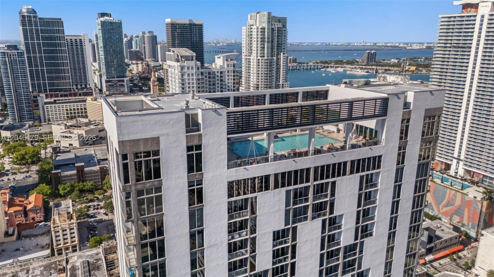 An aerial view of a high-rise building featuring a rooftop swimming pool and surrounding cityscape — 151 SE 1st St, Miami FL 33131, MIAMI, FL
