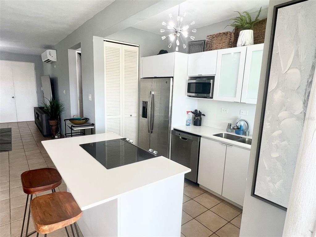 A modern kitchen features white cabinets, stainless steel appliances, and a central island with seating — 180 PALMAS DRIVE UNIT 38-D, HUMACAO, PR