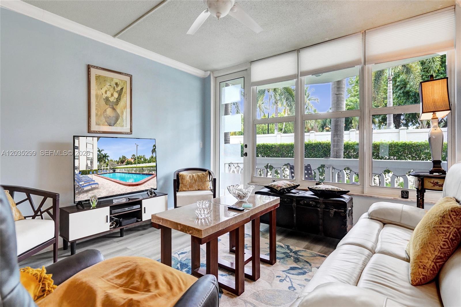 A living room features light blue walls, a marble coffee table, and large windows — 3181 S Ocean Dr # 107, Hallandale Beach FL 33009, HALLANDALE BEACH, FL