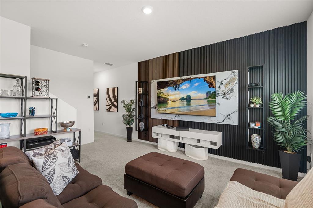 A living room features a dark slatted accent wall with a mounted television and shelving — 8720 SPORTSMAN LOOP, GROVELAND, FL