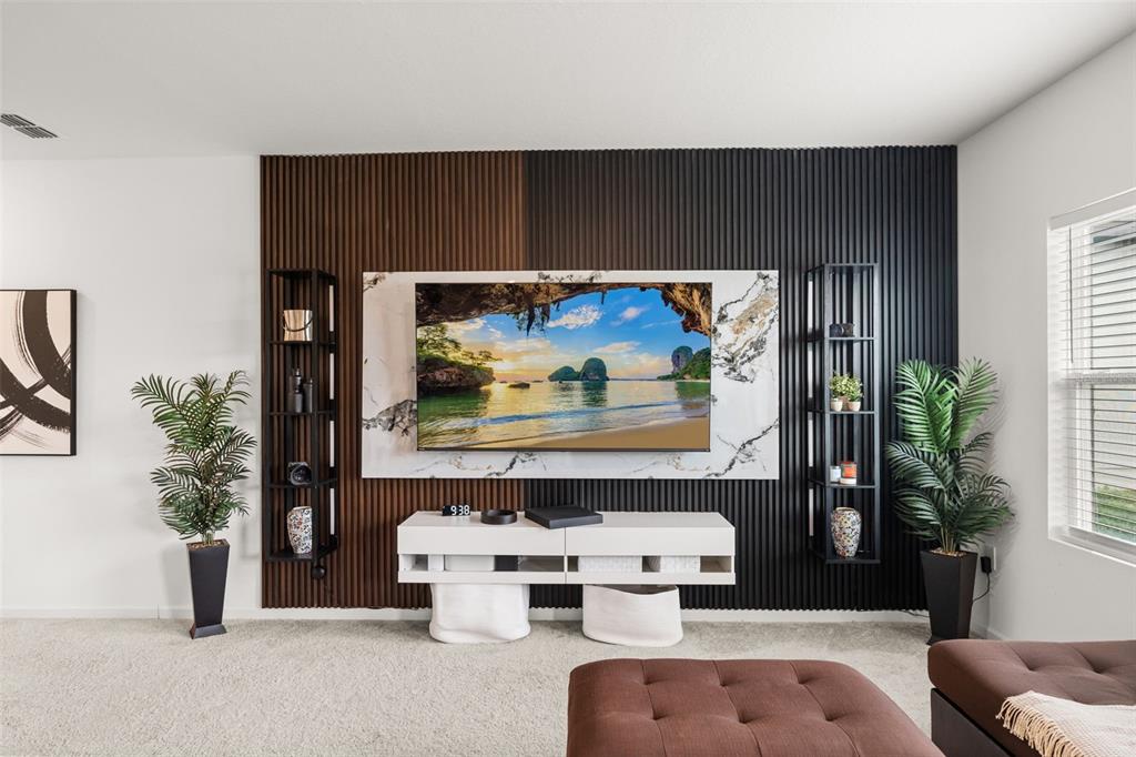 A living room features a television mounted on a marble panel against slatted wood walls — 8720 SPORTSMAN LOOP, GROVELAND, FL