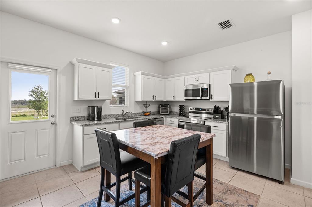 A kitchen features white cabinets, granite countertops, stainless steel appliances, and a central dining island — 8720 SPORTSMAN LOOP, GROVELAND, FL