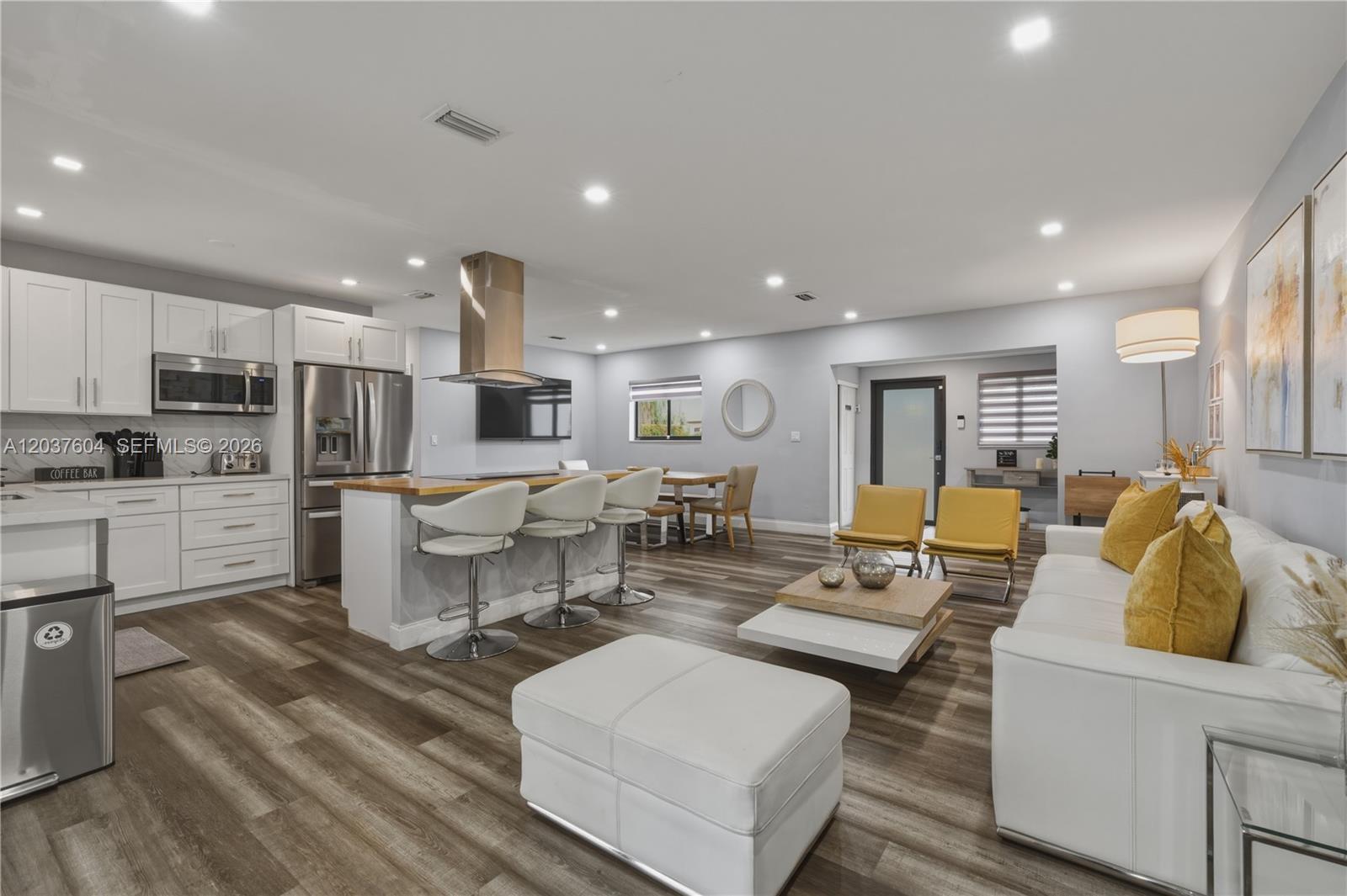 An open-concept kitchen and living area features white cabinetry, a kitchen island, and wood-look flooring — 7395 SW 39th St, Miami FL 33155, MIAMI, FL