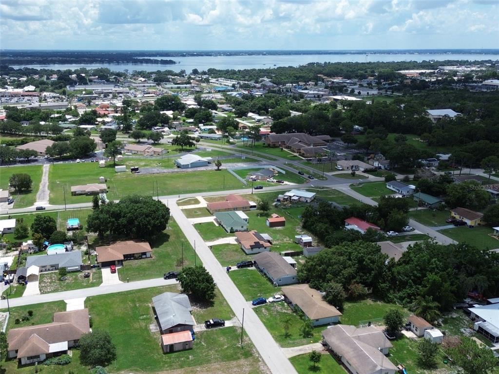 An aerial view shows a residential neighborhood with houses, green lawns, and a distant lake — 3321 DAUPHINE STREET, SEBRING, FL