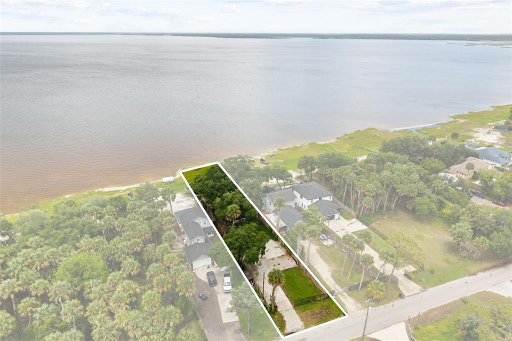 An aerial view shows a long, narrow waterfront lot with trees and a small lawn — 2462 FORT LANE ROAD, GENEVA, FL