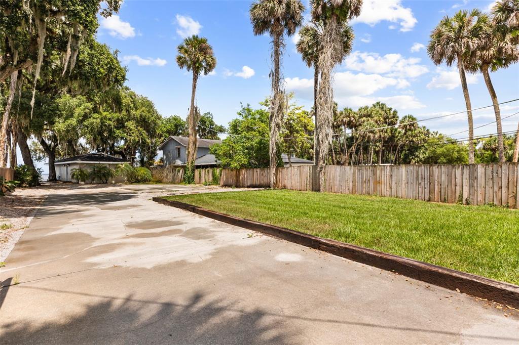 A concrete driveway leads toward a house behind a wooden fence and palm trees — 2462 FORT LANE ROAD, GENEVA, FL