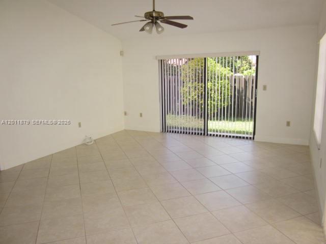 An empty living room features white walls, beige tile flooring, a ceiling fan, and sliding doors — 8853 SW 112 PL, Miami FL 33176, MIAMI, FL