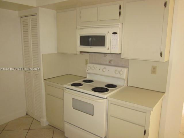 A kitchen features white cabinets, a white electric stove, and a mounted microwave — 8853 SW 112 PL, Miami FL 33176, MIAMI, FL