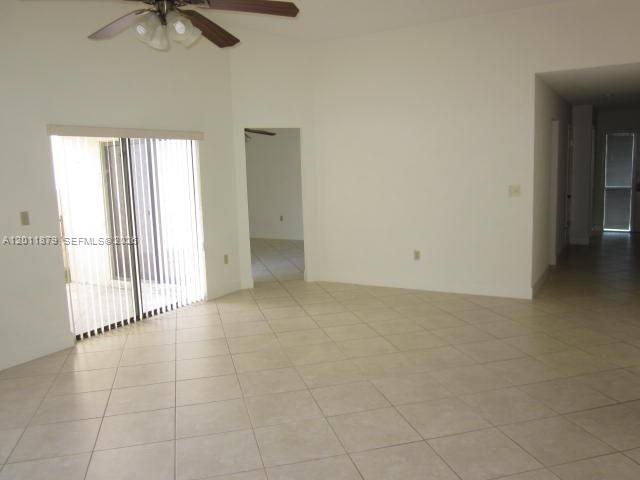 An empty room with light-colored tile flooring, a ceiling fan, and a sliding glass door — 8853 SW 112 PL, Miami FL 33176, MIAMI, FL