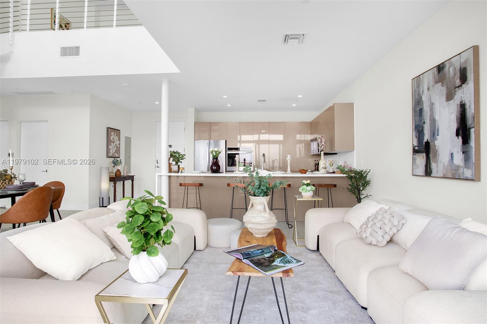 A modern open-concept living room features a kitchen with tan cabinetry and a breakfast bar — 2000 Metropica Way, Sunrise FL 33323, SUNRISE, FL