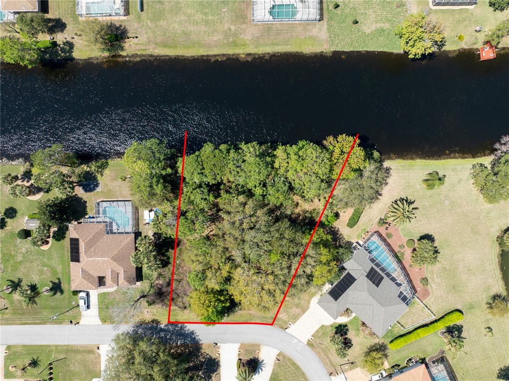 This aerial view shows a vacant, wooded residential lot situated along a canal — 37 LUDLOW LANE W, PALM COAST, FL