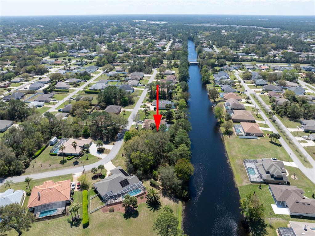 An aerial view shows a residential neighborhood with houses along a canal — 37 LUDLOW LANE W, PALM COAST, FL