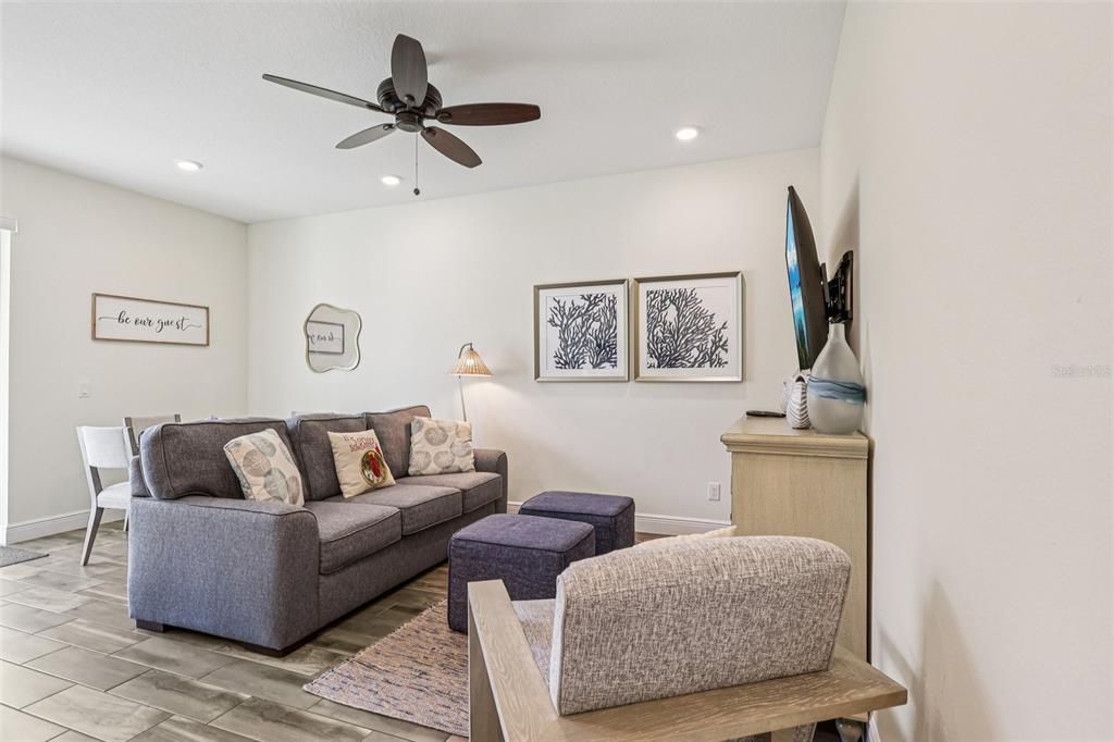 A living room features a gray sofa, two ottomans, a television, and a ceiling fan — 2968 ON THE ROCKS POINT, KISSIMMEE, FL