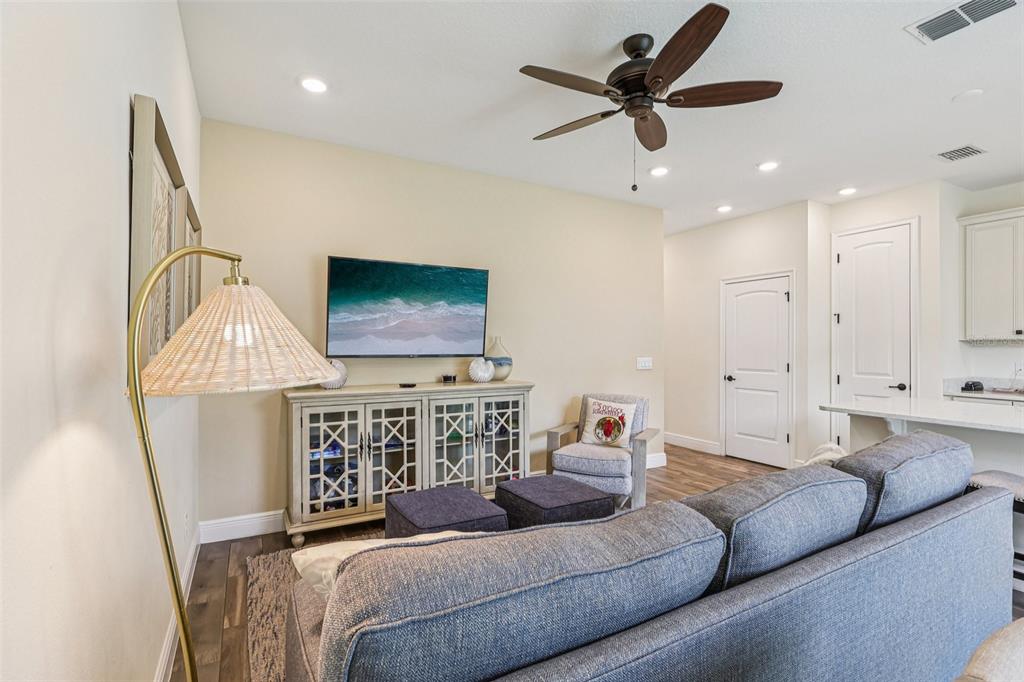 A living room features a gray sofa, a media console, a television, and a ceiling fan — 2968 ON THE ROCKS POINT, KISSIMMEE, FL