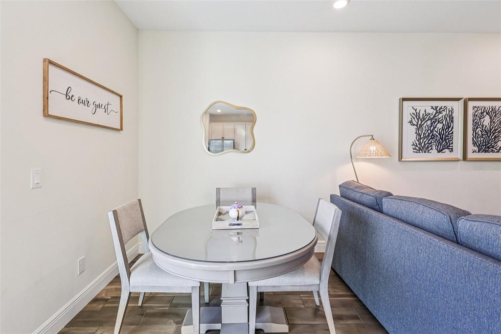 A dining area features a glass-topped oval table, light-colored chairs, and a blue sofa — 2968 ON THE ROCKS POINT, KISSIMMEE, FL