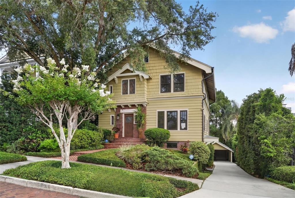 A two-story yellow house with a brick porch and a driveway leading to a garage — 705 TERRACE BOULEVARD, ORLANDO, FL