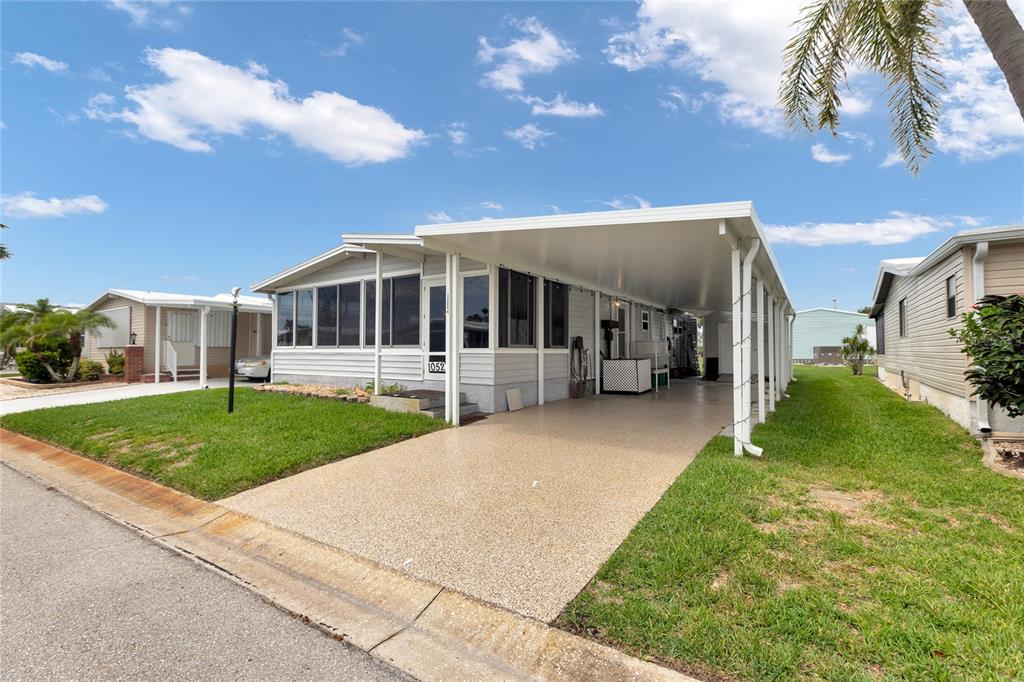A single-story manufactured home features a screened-in porch, a covered carport, and a concrete driveway — 2100 KINGS HIGHWAY UNIT 1052, PORT CHARLOTTE, FL