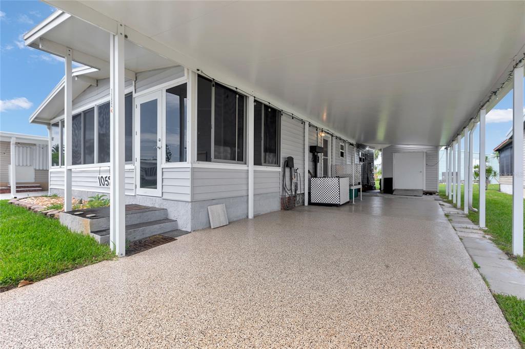 A light gray mobile home features a large covered carport and a screened-in front porch — 2100 KINGS HIGHWAY UNIT 1052, PORT CHARLOTTE, FL
