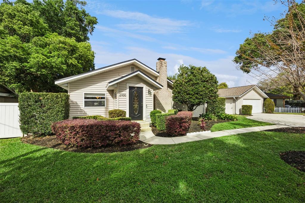 A single-story house with beige siding, a brick chimney, and a front lawn — 2100 MAE STREET, ORLANDO, FL