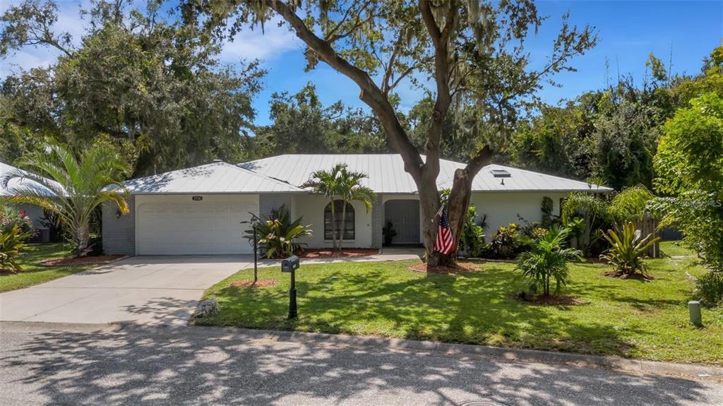 A single-story house with a white metal roof, a two-car garage, and a large tree — 3736 MAPLE HOLLOW COURT, SARASOTA, FL