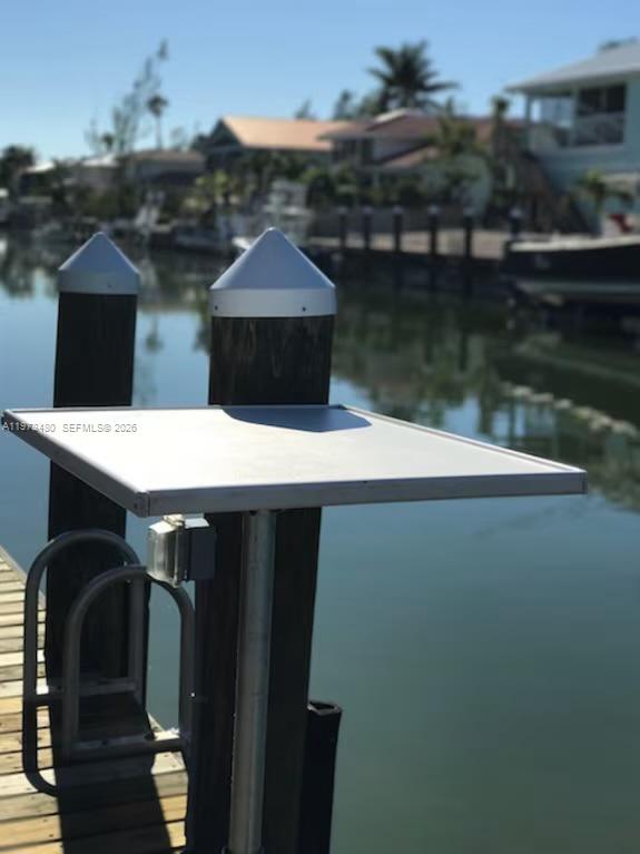 A metal cleaning table stands on a wooden dock overlooking a canal with houses — 227 Sombrero Beach Rd, Marathon FL 33050, MARATHON, FL