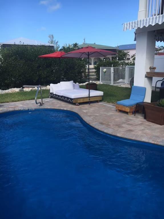 A swimming pool sits in front of a patio with a daybed and lounge chair — 227 Sombrero Beach Rd, Marathon FL 33050, MARATHON, FL