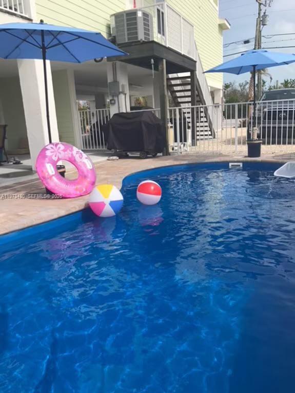 A swimming pool with two beach balls and a pink pool float sits outdoors — 227 Sombrero Beach Rd, Marathon FL 33050, MARATHON, FL