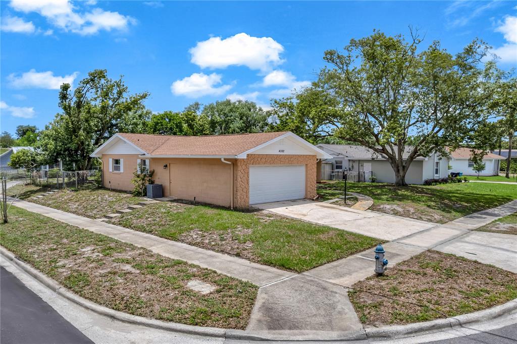 A single-story house with a tan exterior, stone-accented garage, and a concrete driveway — 4992 E WIND STREET, ORLANDO, FL