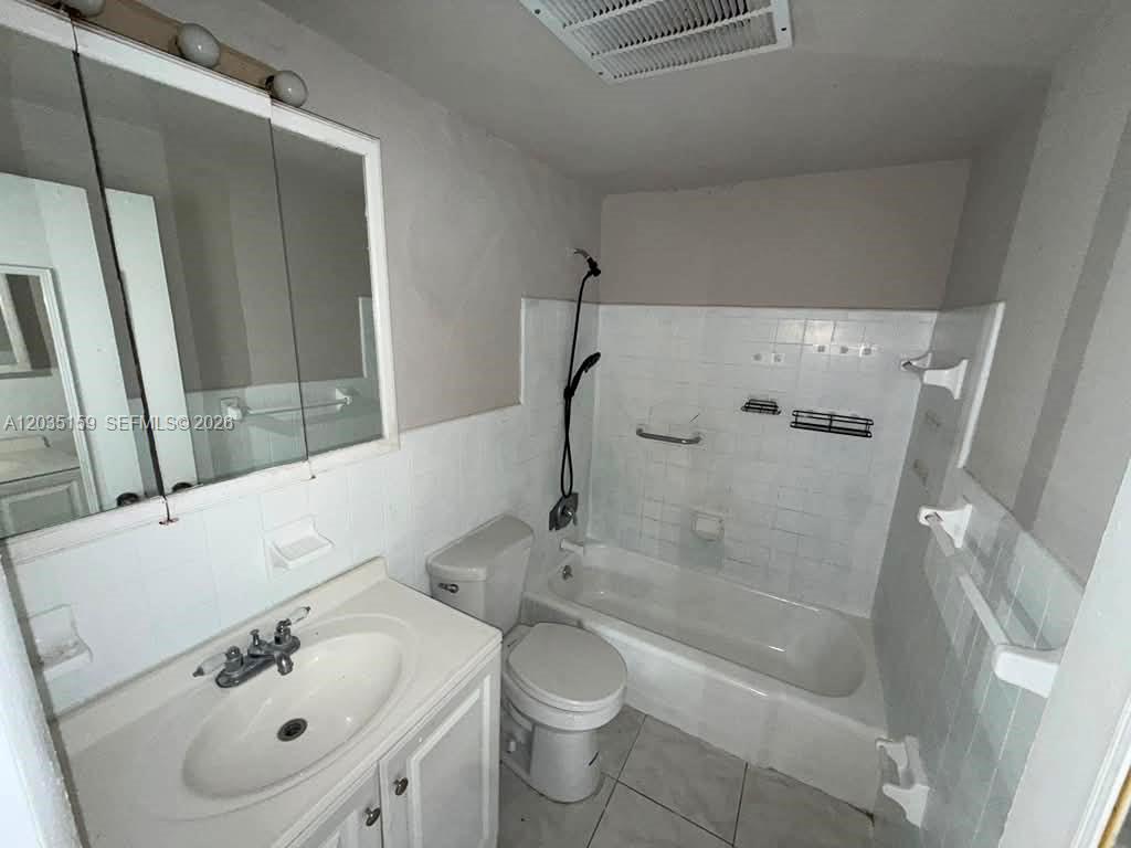 A bathroom features a white vanity, a toilet, and a shower-tub combination with white tiles — 2917 Plunkett St # 15C, Hollywood FL 33020, HOLLYWOOD, FL