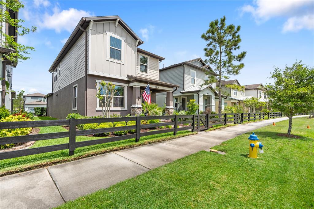 A two-story house with a black fence, American flag, and fire hydrant on the lawn — 11874 BLAMEY TRAIL, ODESSA, FL