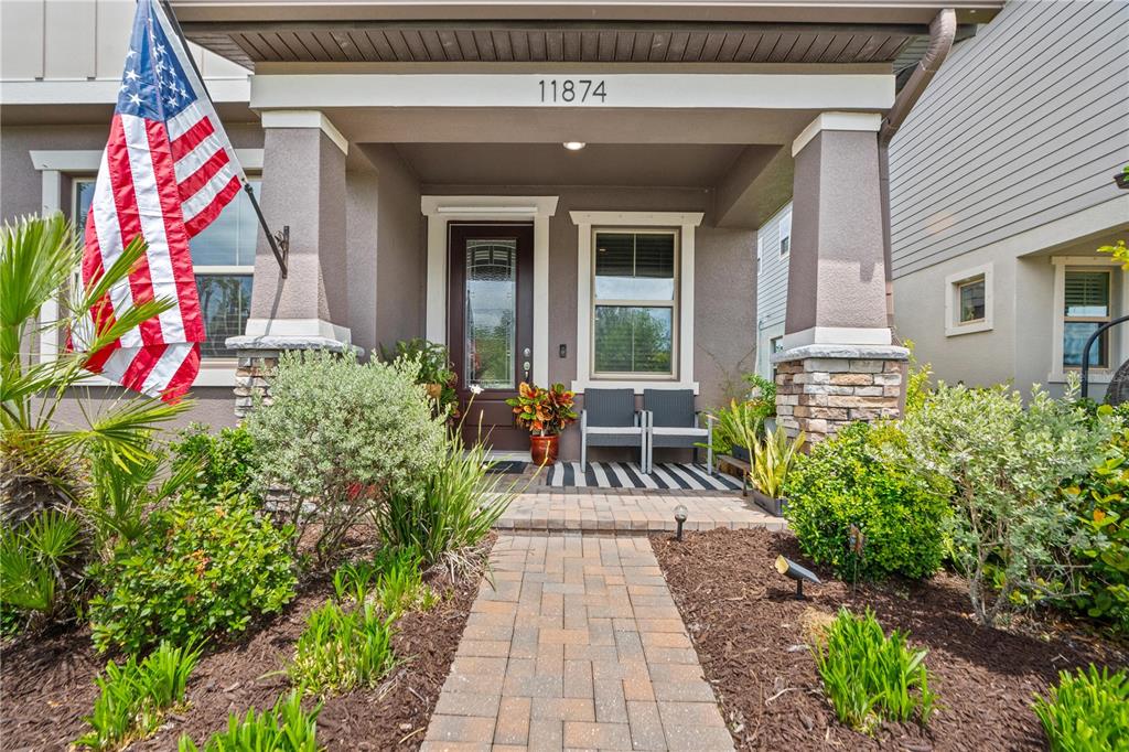 A paved walkway leads to the covered front porch of a house with stone pillars — 11874 BLAMEY TRAIL, ODESSA, FL