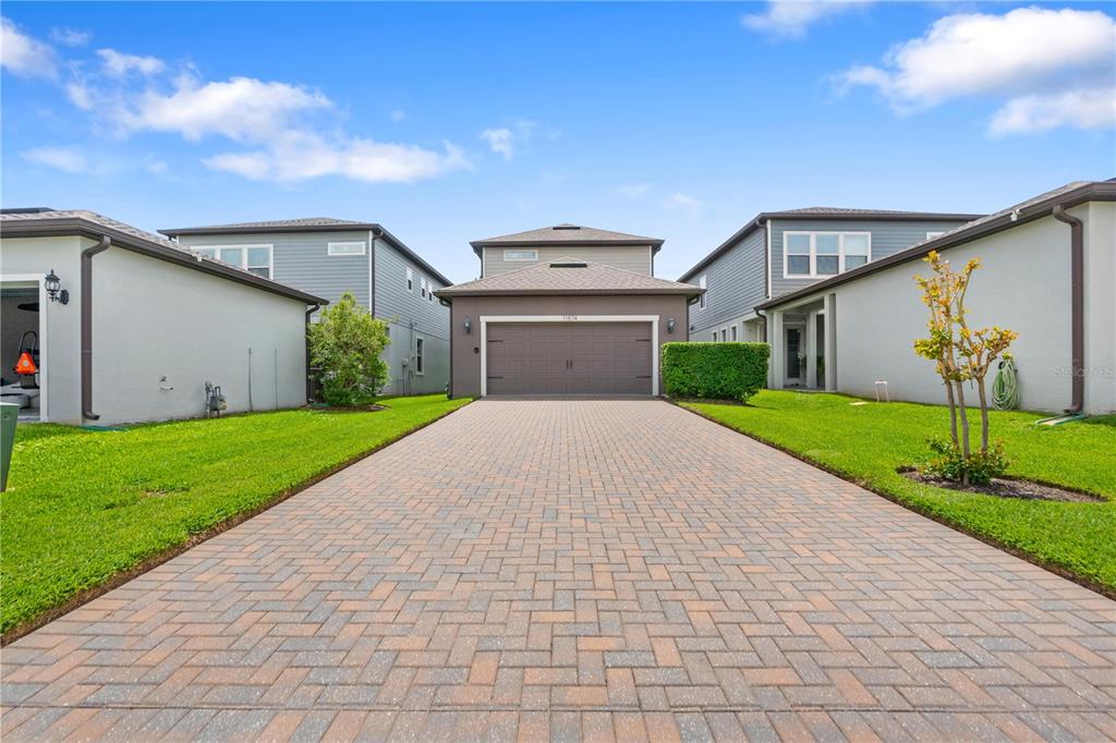 A paved driveway leads to the garage of a two-story house between two neighboring homes — 11874 BLAMEY TRAIL, ODESSA, FL