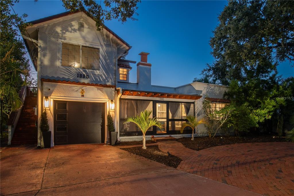 A two-story house with a garage, a screened-in porch, and a brick driveway at dusk — 1880 N WASHINGTON AVENUE, CLEARWATER, FL