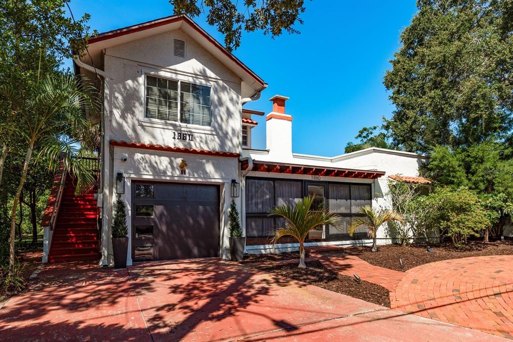 A two-story house with a garage, red stairs, and a brick driveway under a blue sky — 1880 N WASHINGTON AVENUE, CLEARWATER, FL