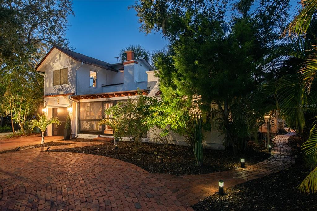 A two-story house with a brick driveway and a screened front porch at dusk — 1880 N WASHINGTON AVENUE, CLEARWATER, FL