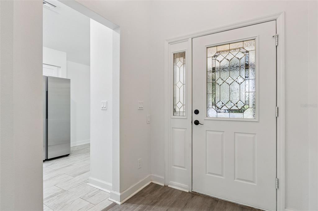 A white front door with a decorative glass insert opens into a tiled entryway — 3022 NEW HAVEN PLACE, MOUNT DORA, FL