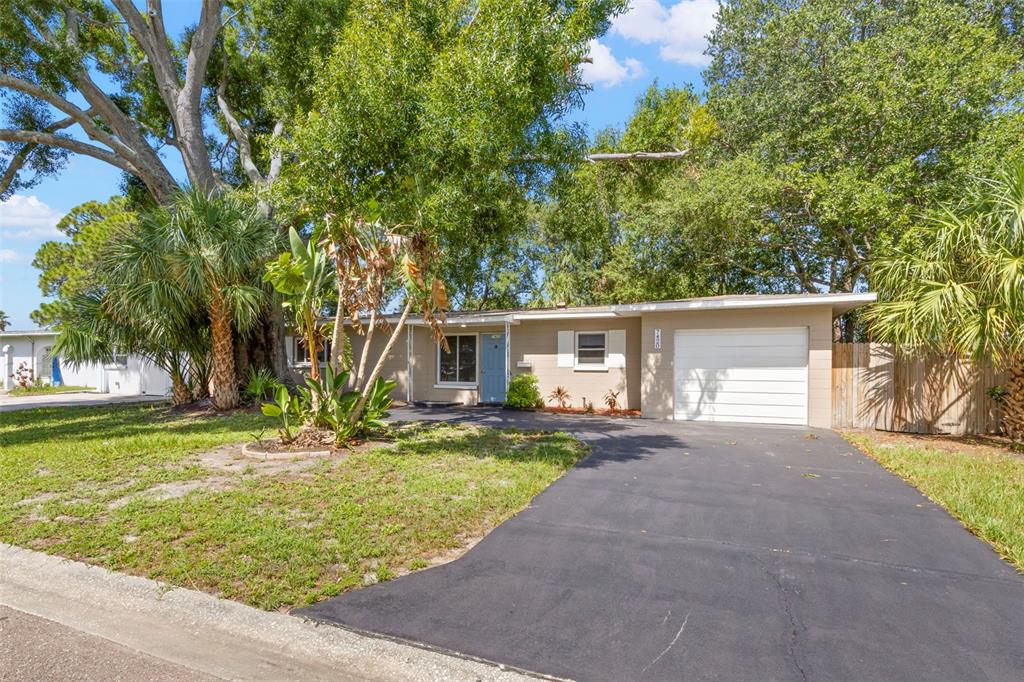 A single-story house with a light-colored exterior, a white garage door, and a paved driveway — 7420 DR MARTIN LUTHER KING JR STREET N, ST PETERSBURG, FL