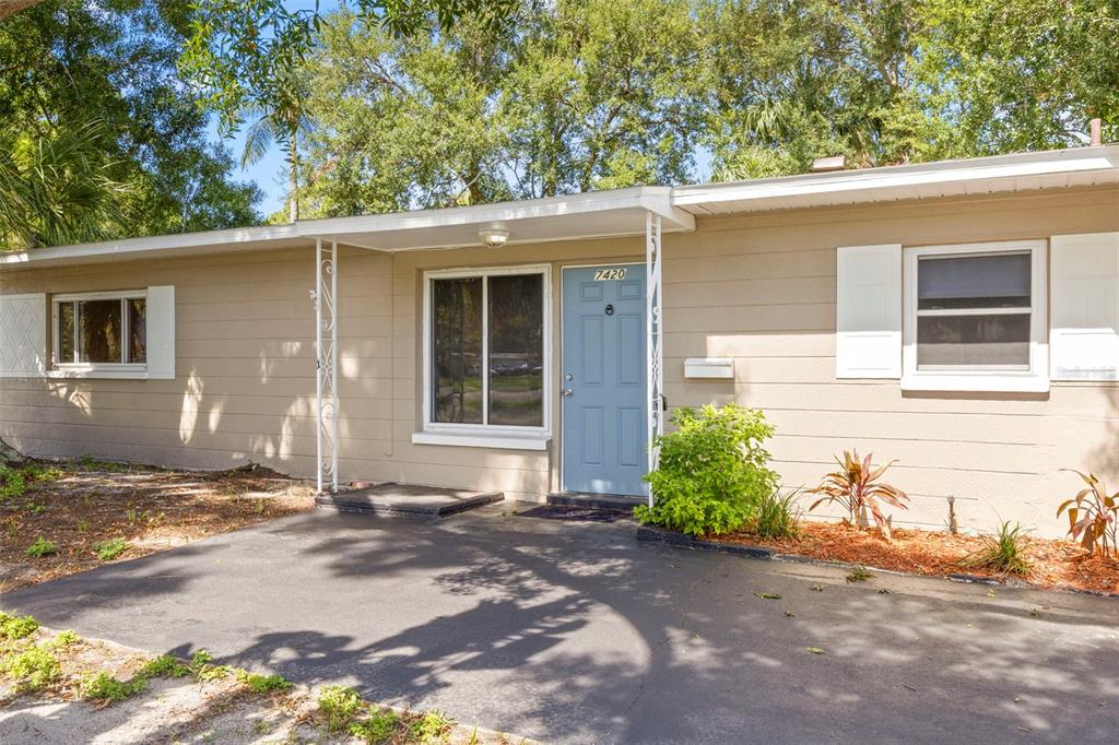 A single-story house with tan siding, a light blue front door, and a paved driveway — 7420 DR MARTIN LUTHER KING JR STREET N, ST PETERSBURG, FL