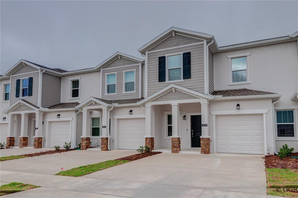 A row of modern two-story townhouses with light-colored siding, stone accents, and attached garages — 3243 LAURENT LOOP, DAVENPORT, FL