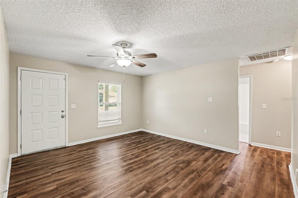 An empty living room features wood-look flooring, a ceiling fan, and a white front door — 2345 NORTHVIEW DRIVE, LAKELAND, FL