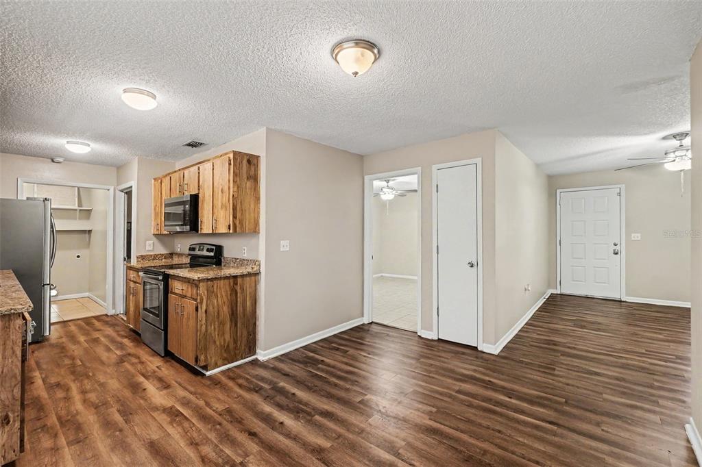 A kitchen with wood cabinets and granite countertops opens into a living area with flooring — 2345 NORTHVIEW DRIVE, LAKELAND, FL