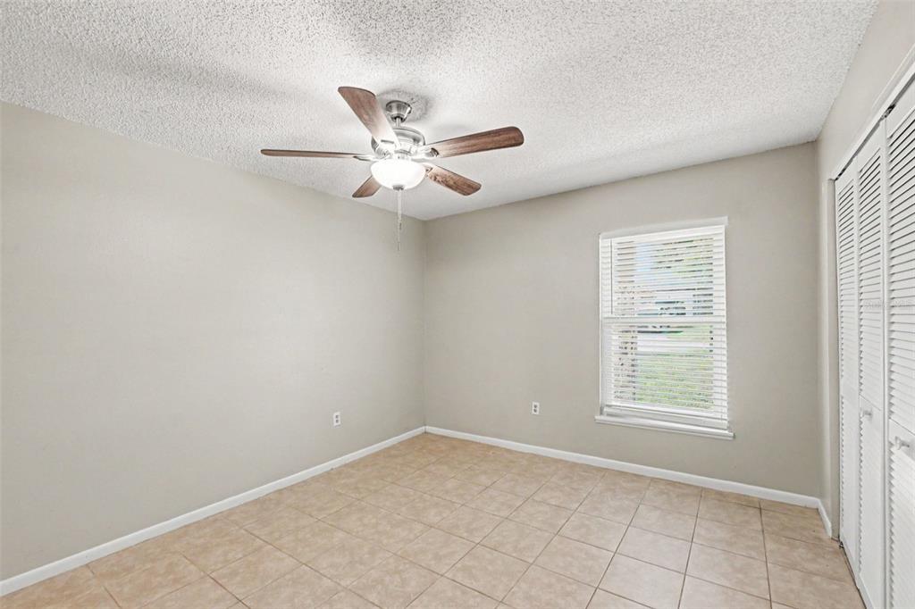 An empty bedroom features beige walls, light tile flooring, a ceiling fan, and white blinds — 2345 NORTHVIEW DRIVE, LAKELAND, FL