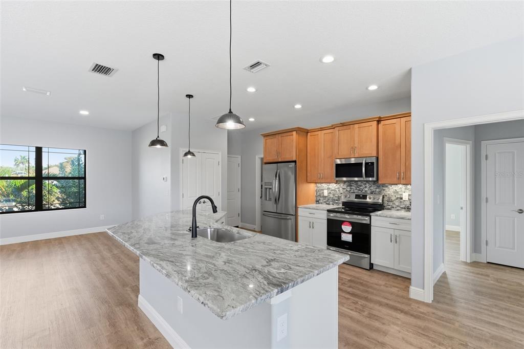 A kitchen features a granite-topped island, stainless steel appliances, and two-toned cabinetry — 14361 FORT MYERS AVENUE, PORT CHARLOTTE, FL