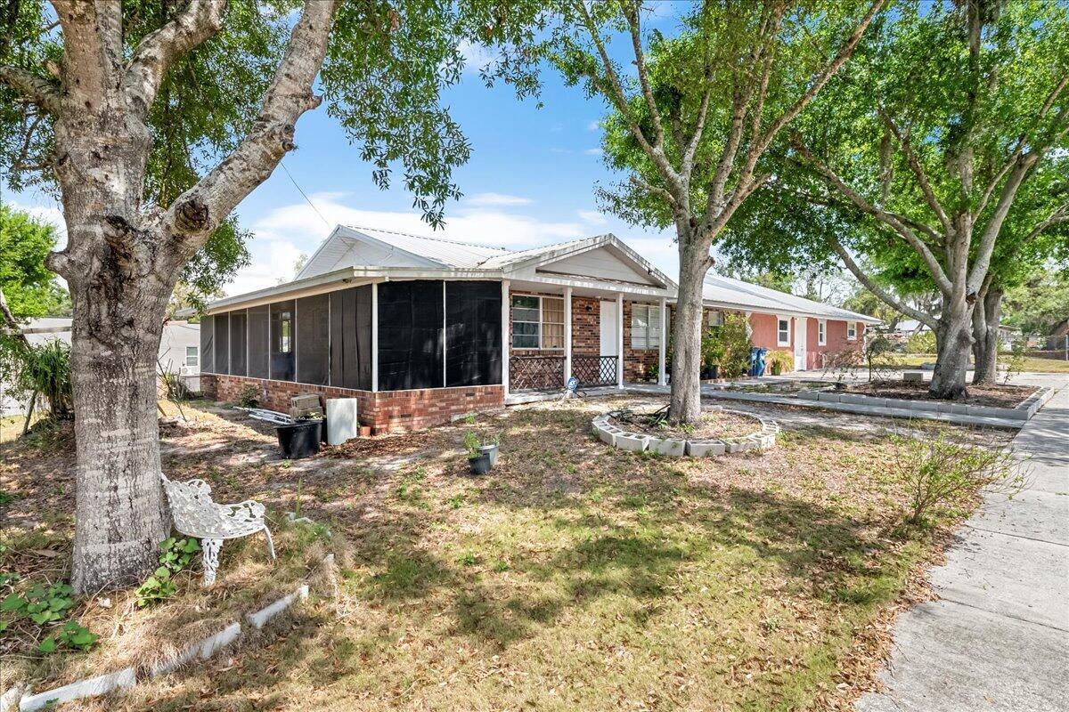 A single-story house with a screened-in porch, brick facade, and large trees in the yard — 216 Micco Avenue, Sebring FL 33870, SEBRING, FL