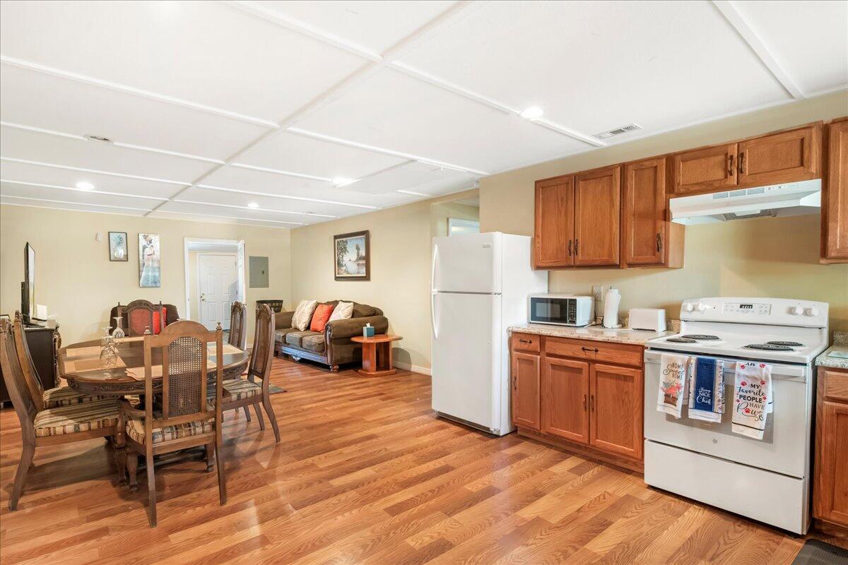 An open-concept kitchen and dining area with wood flooring, wood cabinets, and a white refrigerator — 216 Micco Avenue, Sebring FL 33870, SEBRING, FL