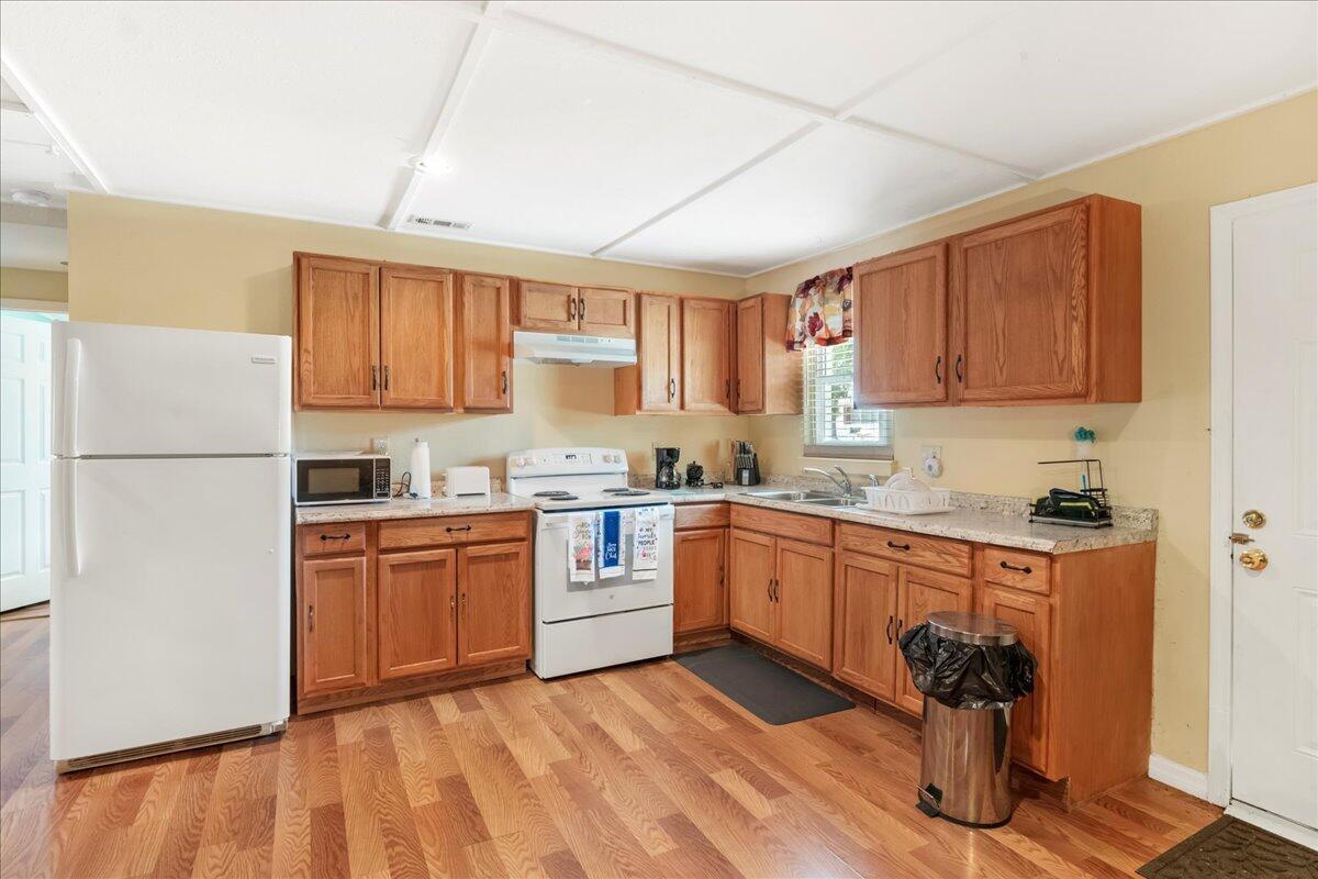 A kitchen with wood cabinets, laminate countertops, white appliances, and wood-look flooring — 216 Micco Avenue, Sebring FL 33870, SEBRING, FL