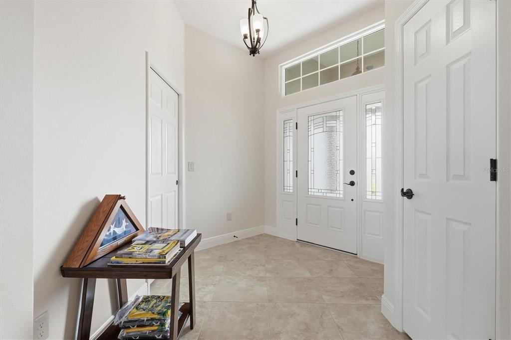 A bright entryway features tile flooring, a white front door with sidelights, and a transom window — 5819 WHITE IBIS RUN, THE VILLAGES, FL