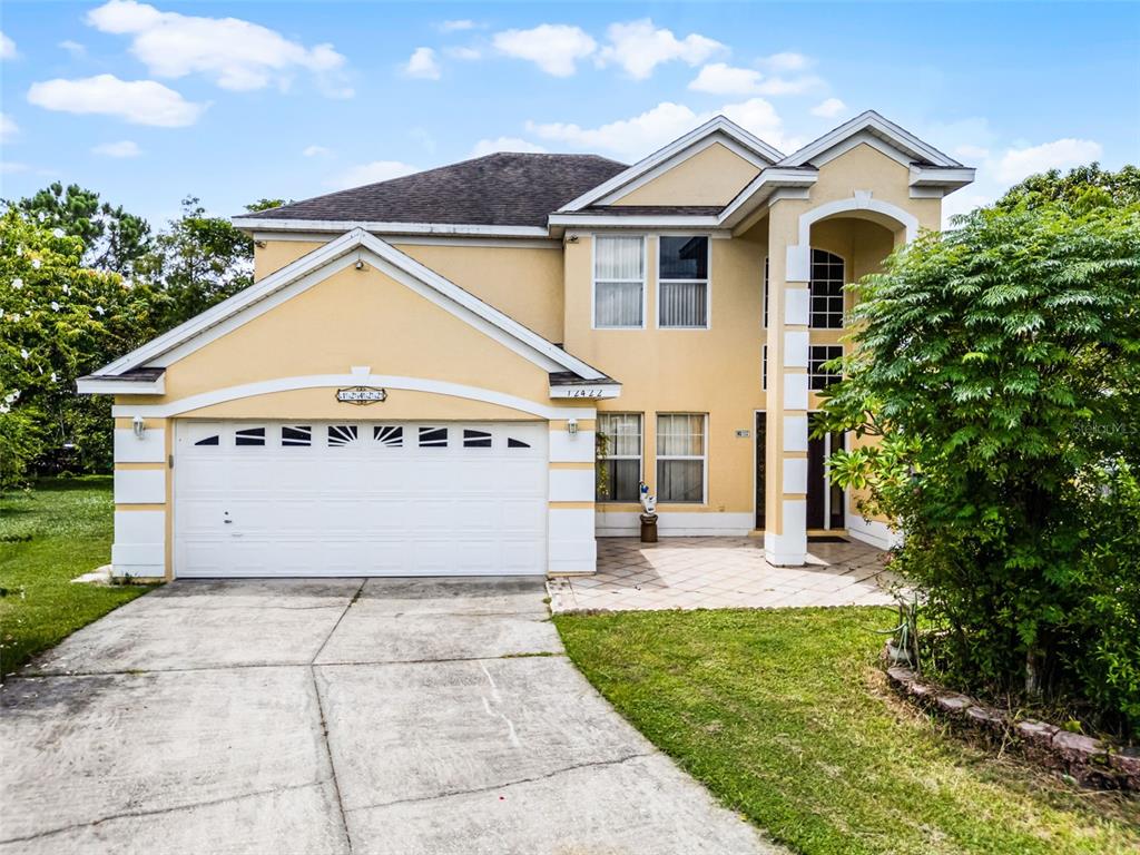 A two-story yellow house with a white garage and a paved driveway — 12422 SION COURT, ORLANDO, FL