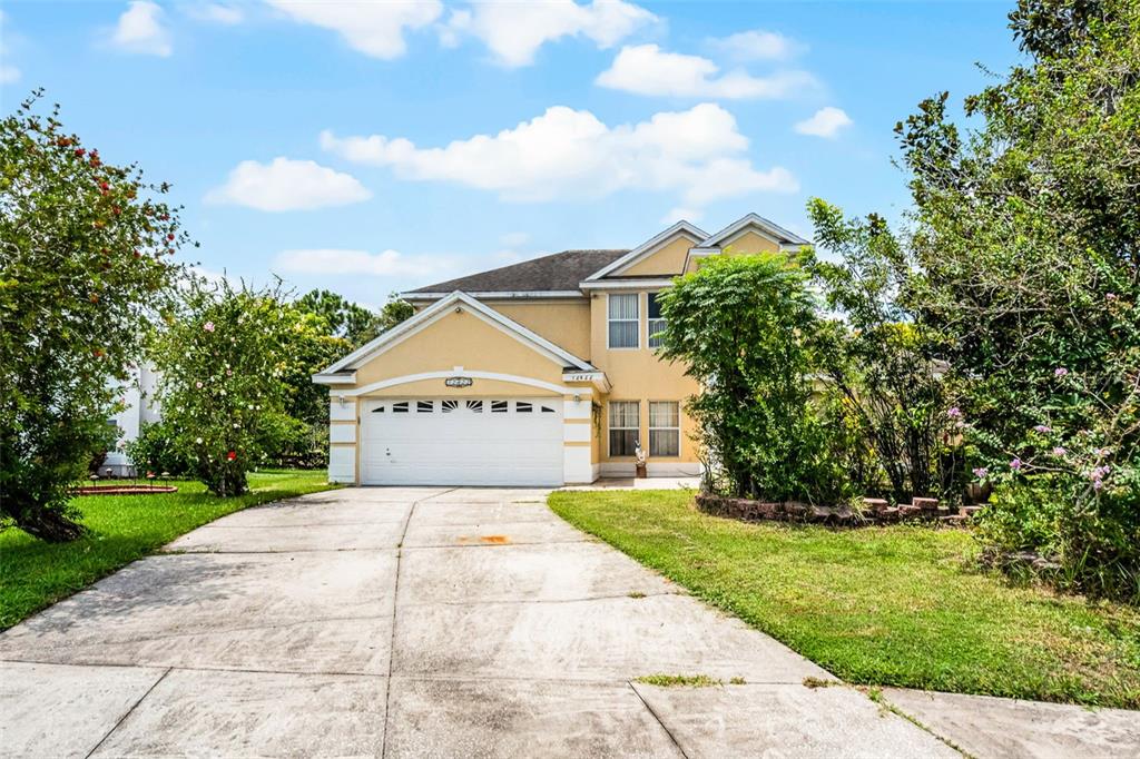 A two-story, yellow-stucco house features a two-car garage and a concrete driveway — 12422 SION COURT, ORLANDO, FL