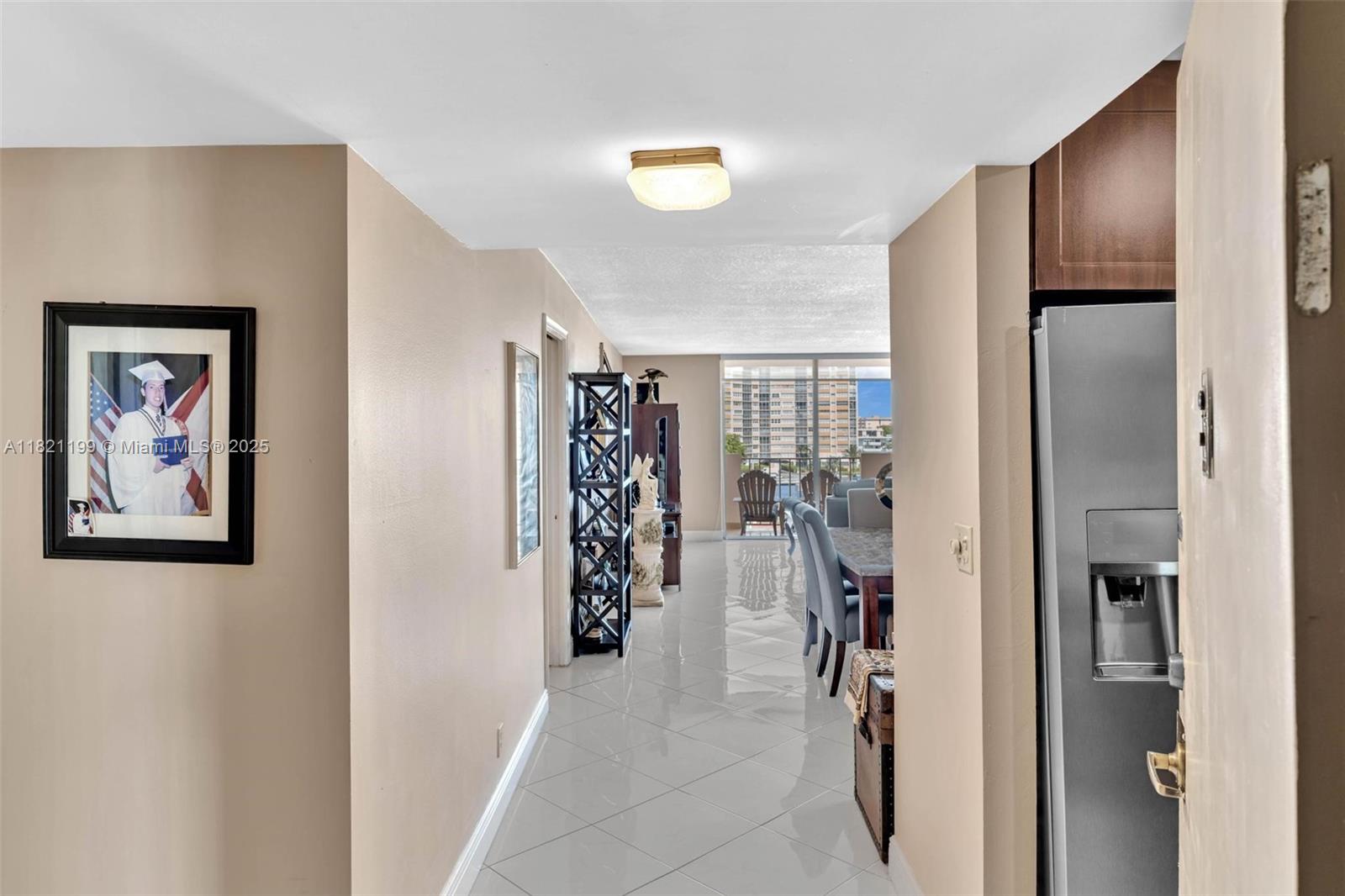 A hallway with white tile floors leads to a dining area and a balcony view — 1865 S Ocean Dr # 5J, Hallandale Beach FL 33009, HALLANDALE BEACH, FL
